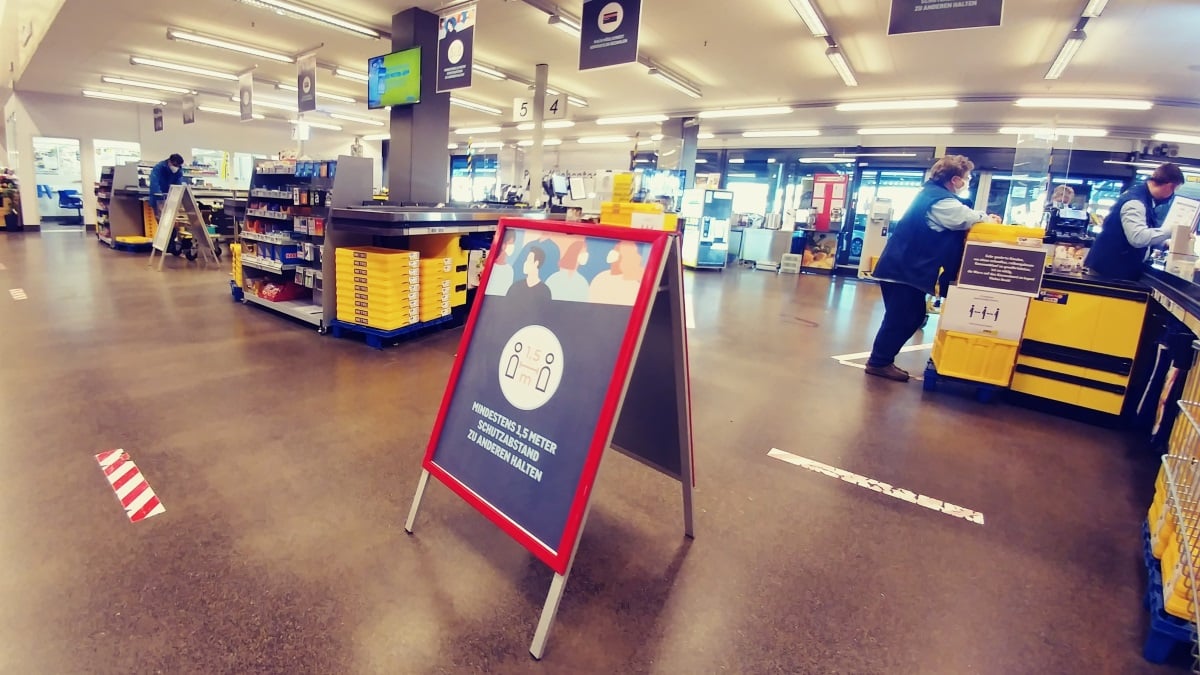 Ein Schild weist in einem Einkaufsmarkt auf die Abstandsregeln im Rahmen der Coronamaßnahmen hin.