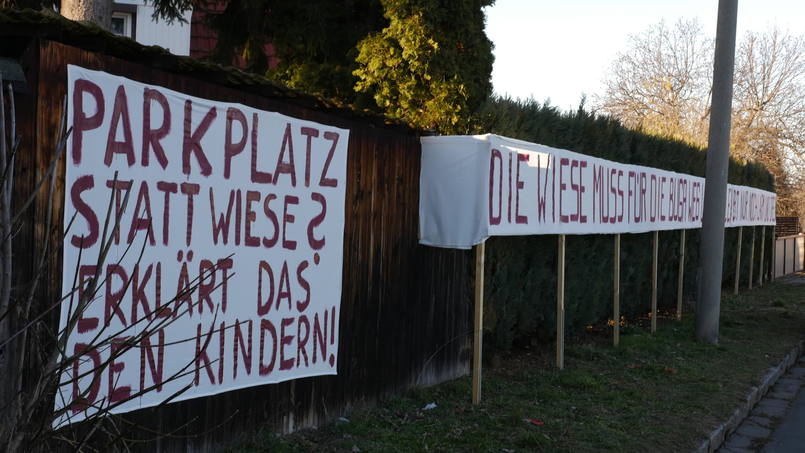 Anwohner protestieren mit einem Plakat gegen den Umbau einer Wiese zu einem Parkplatz. Erfurt 2019.