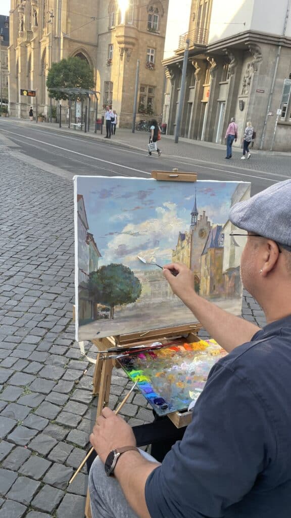 Der Maler Valerij Solovey malt das Rathaus auf dem Fischmarkt
