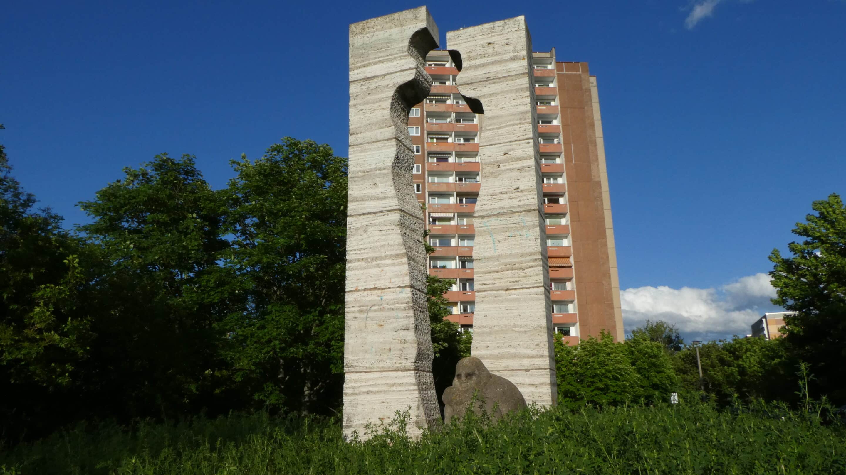 Denkmal Herrenberg mit Hochhaus und Skulptur.