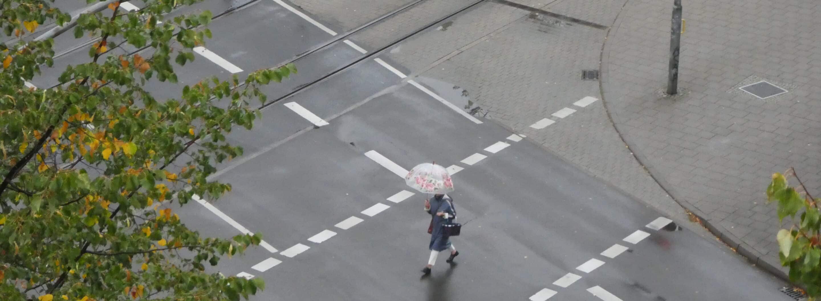 Eine Frau läuft mit Schirm über den Juri Gagarin Ring in Erfurt