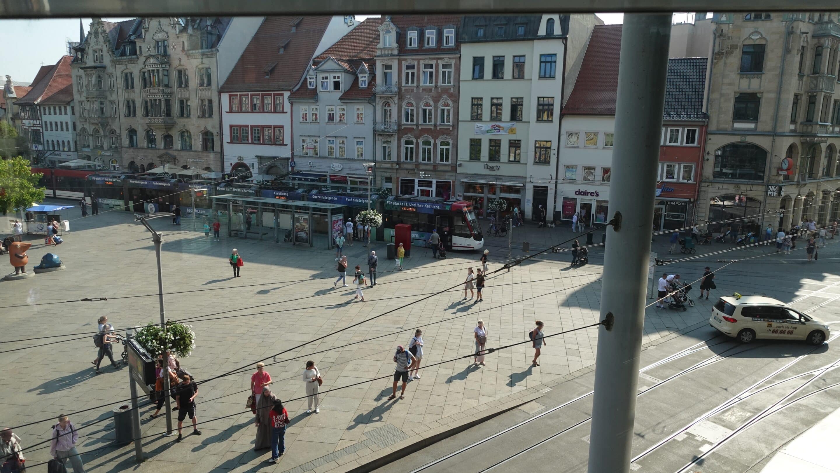 Everyday life on the Anger in Erfurt with people waiting at the tram stop.