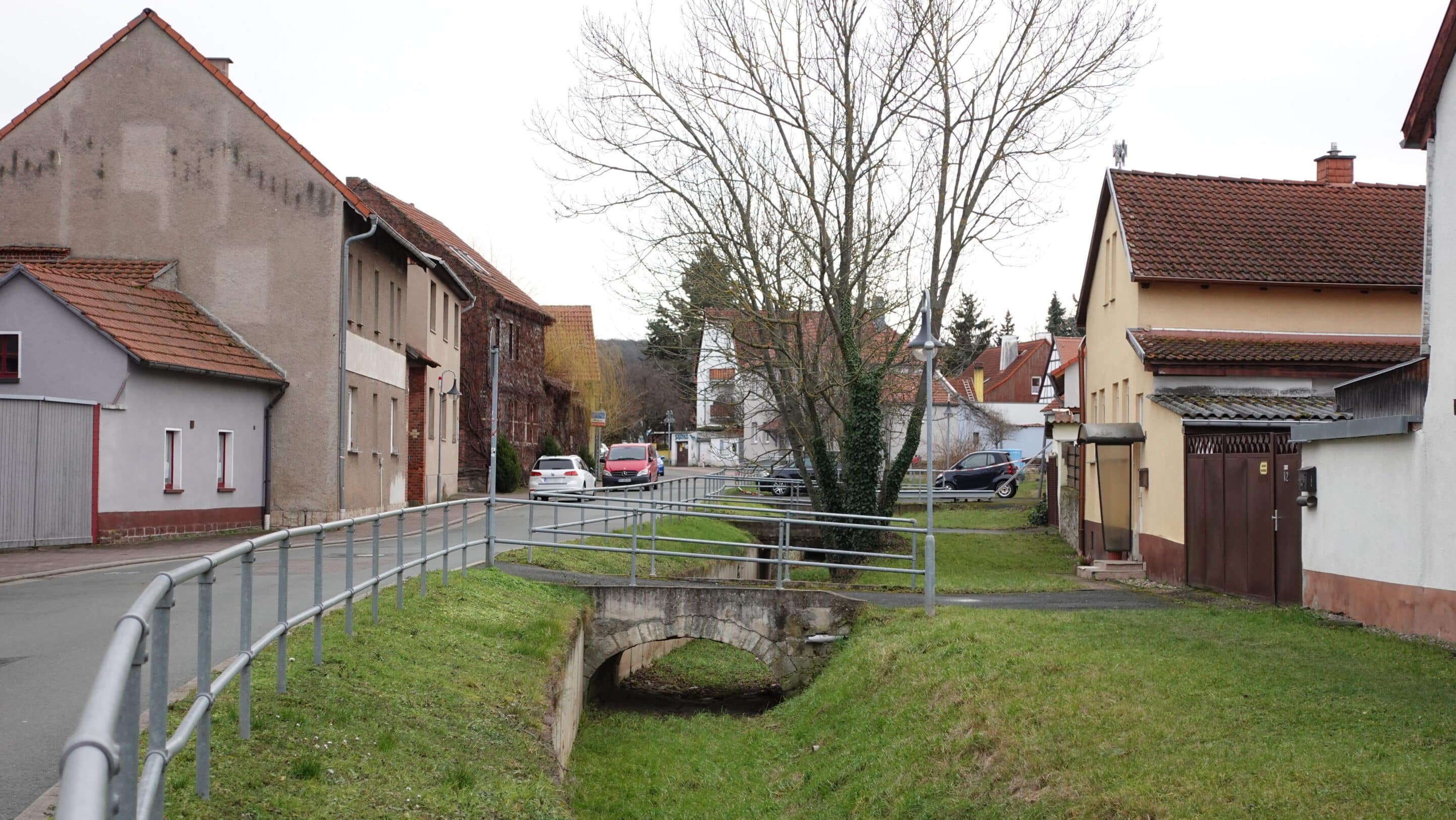 Die Straße Am Pfingstbach in Niedernissa einem Ortsteil der Landeshauptstadt von Thüringen Erfurt mit Bach und Straße.