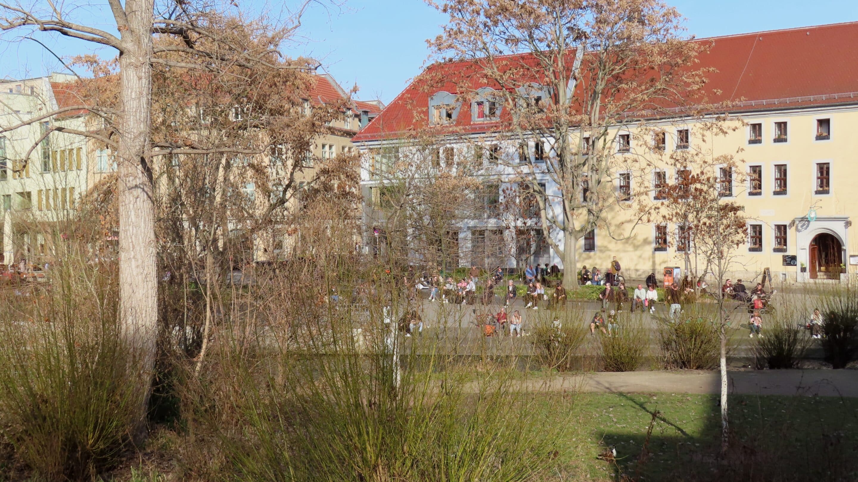 Menschen genießen die erste Frühlingssonne hinter der Krämerbrücke in Erfurt.